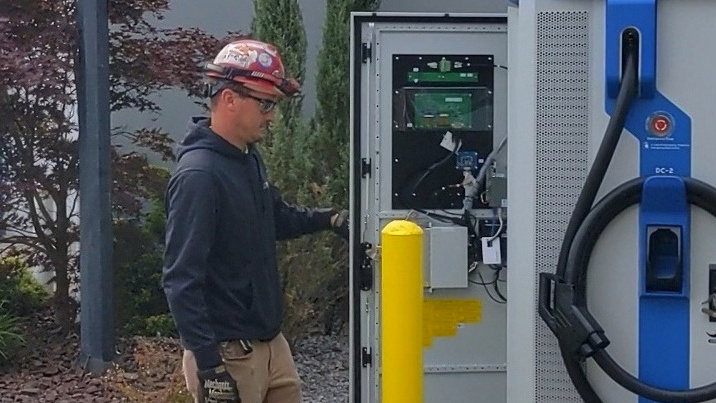 Union electrician inspects interior of commercial EV charger at Chevrolet dealership